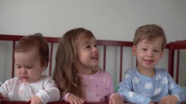 Sevimli, neşeli 3 çocuk kız ve erkek kardeş gri bebek beşikteki anaokulu çocukları pijamalarıyla uyanıp bacaklarını sallayarak uyanmışlar. Çocukluk, rahatlık, rahatlık, ilaç, sağlık konsepti