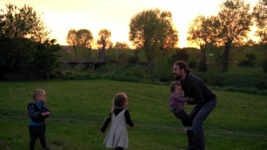 Parktaki insanlar. Gün batımında mutlu aile silueti. Babasının çocuğu havaya atması çok zaman aldı. Aileler ve eğlenceli çocuklar açık havada yürüyorlar. Babalar Günü, çocukluk, ebeveynlik kavramı.