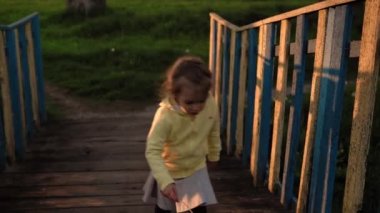 Otantik, küçük, şirin, anaokulu çocuğu kız ve erkek kardeş bahar günbatımında parkta yürüyorlar. Çocuklar nehrin üzerinden eski ahşap köprüyü geçerken bir şey bulmuşlar. Çocukluk, ebeveynlik, aile, yaşam tarzı konsepti