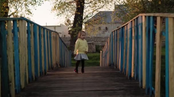 Auténticos niños pequeños preescolares lindo hermano niña y niño caminando en el parque al atardecer de primavera. Los niños cruzan un viejo puente de madera sobre el río encuentran algo. Infancia, paternidad, familia, concepto de estilo de vida — Vídeos de Stock