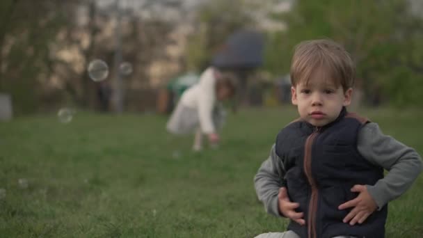 Kleine Vorschulkinder Geschwister Kinder Jungen und Mädchen fangen Seifenblasen im Frühling Park bei Sonnenuntergang. Glückliche Kinderfreunde haben Spaß dabei. Freizeit Natur. Familie, Freundschaft, Kindheitskonzept — Stockvideo