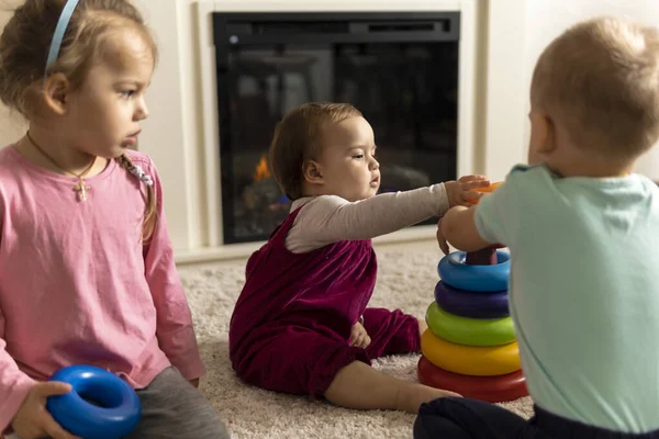 Familia, amigos, amistad, infancia, desarrollo, habilidades, juegos de motilidad - niños pequeños niños auténticos niños pequeños pone anillos en la pirámide jugando juntos con juguete sentarse en el suelo en casa acogedora — Foto de Stock