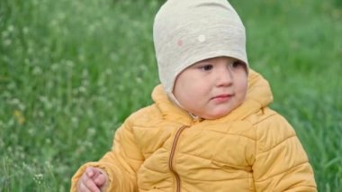 Otantik, küçük, sarı elbiseli kız bebek bahar günbatımında uzun çimenlerin üzerinde parkta yürüyor. Güneşin doğuşu sırasında doğada oyun oynayan çocuk Crawley çimenliği. Çocukluk, ebeveynlik, aile, yaşam tarzı konsepti