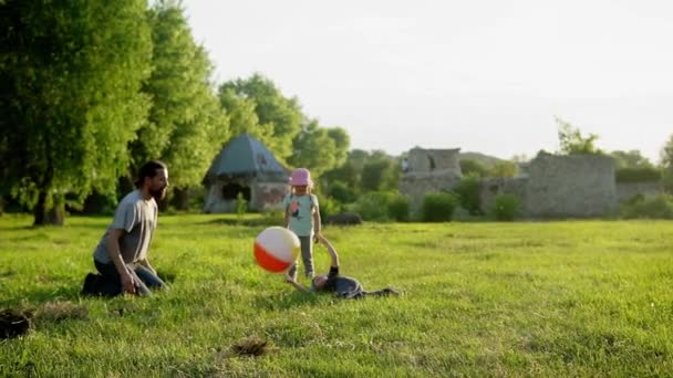 Zomer, vakantie, natuur, gelukkig gezin, kindertijd, vaderschap, vaderdag - Papa met kleine kleuter kleuter kinderen lopen plezier spelen met grote opblaasbare bal in het park bij zonsondergang buiten — Stockvideo