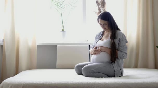 Embarazo, maternidad, personas, concepto de expectativa - mujer embarazada feliz tocando su barriga en la cama en casa caricias madre desnuda barriga grande con las manos, en la habitación de luz en el día de verano soleado — Vídeo de stock