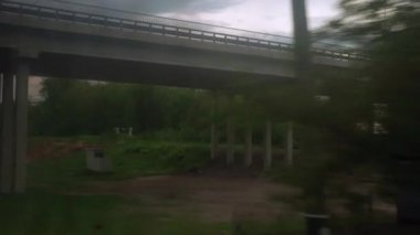Yüksek hızlı trenin penceresinden, yaz arkaplanındaki güzel bulutlu gökyüzünün üzerinde köprü altından geçen camların üzerindeki parlaklıkla manzara. Ulaşım, seyahat, demiryolu, yol, zina kavramı