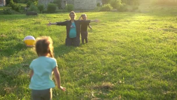 Лето, природа, счастливая семья, День матери - беременная мама с двумя детьми-малышами, бегущими за руки на лугу в парке на закате. Счастливые улыбающиеся дети веселятся, смеются, проводят время вместе — стоковое видео