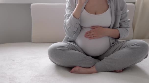 Autentyczne słodkie kobiety w ciąży czuje się szczęśliwy w domu z brzucha. Młoda matka głaskająca brzuch i pijąca wodę ze szkła przy oknie. macierzyństwo, ciąża, macierzyństwo, koncepcja stylu życia — Wideo stockowe