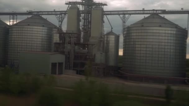 Uitzicht vanuit het raam van hogesnelheidstrein op landschap van oude roestige boxcars en stalen korrel silo 's op prachtige bewolkte blauwe lucht in de zomer achtergrond. Vervoer, vervoer, spoor, weg, hoererij — Stockvideo