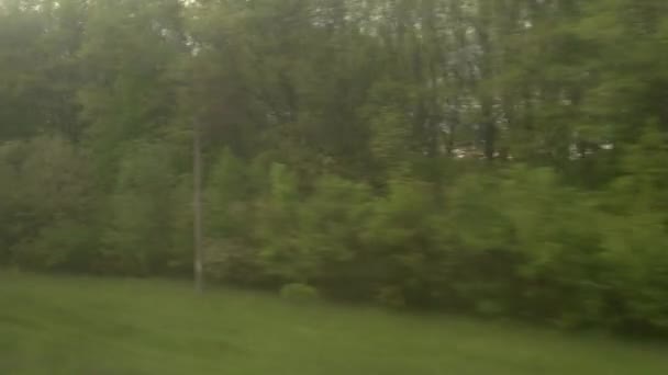Vista da janela do trem de velocidade com brilho em vidro na bela paisagem do prado e floresta céu nublado pôr do sol no verão natureza fundo. Transporte, viagens, estrada, ferrovia, conceito de comnicação — Vídeo de Stock