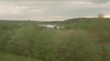 Yüksek hızlı trenin penceresinden manzarası güzel doğa manzarası vahşi arazi ve orman akşam bulutlu gökyüzü günbatımı yaz arkaplanında. Ulaşım, seyahat, demiryolu, iletişim konsepti