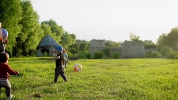 Zomer, vakantie, natuur, gelukkig gezin, kindertijd, vaderschap, vaderdag - Papa met kleine kleuter kleuter kinderen lopen plezier spelen met grote opblaasbare bal in het park bij zonsondergang buiten — Stockvideo