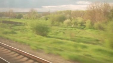 Yüksek hızlı trenin penceresinden manzarası güzel doğa manzarası vahşi arazi ve orman akşam bulutlu gökyüzü günbatımı yaz arkaplanında. Ulaşım, seyahat, demiryolu, iletişim konsepti