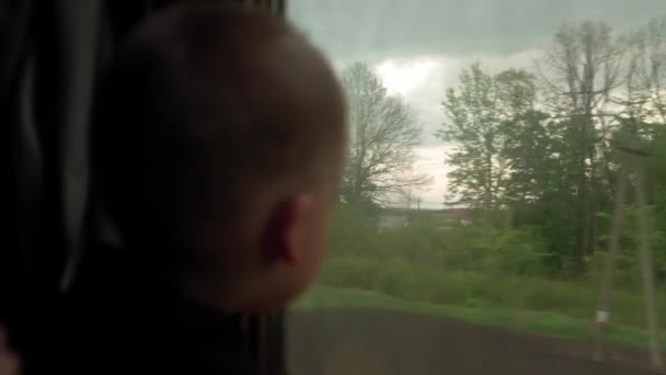 Nahaufnahme kleine Vorschulkind niedlichen Jungen Blick aus dem Zugfenster. Blick vom Hochgeschwindigkeitszug auf die Landschaft des schönen Naturfeldes vor Sonnenuntergang. Verkehr, Reisen, Straße, Schiene, Vernetzungskonzept — Stockvideo