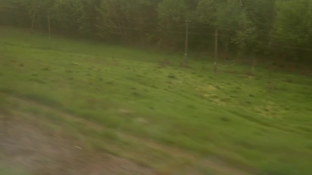 从高速列车窗口眺望美丽的自然风光，在暮色黄昏的天空落日的背景下，山路上有车有林。运输、旅行、铁路、通信概念 — 图库视频影像