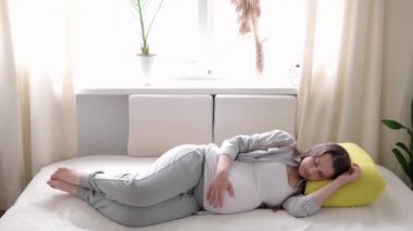 Hamilelik, annelik, insanlar, beklenti konsepti mutlu uykulu hamile kadın karnına dokunuyor evde uykusunda dinleniyor ilgili anne güneşli bir günde dinlenme odasında karnını okşuyor.
