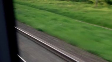 Hızlı trenin camında parlayan ışık ve yaz arkaplanındaki günbatımından önce çayırların ve ormanın manzarasında paralel raylar. Ulaşım, seyahat, yol, demiryolu, zina kavramı