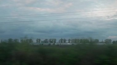 Yüksek hızlı trenin penceresinden manzarası güzel doğa manzarası vahşi arazi ve orman akşam bulutlu gökyüzü günbatımı yaz arkaplanında. Ulaşım, seyahat, demiryolu, iletişim konsepti