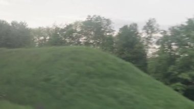 Hızlı trenin camında parlayan ışık ve yaz arkaplanındaki günbatımından önce çayırların ve ormanın manzarasında paralel raylar. Ulaşım, seyahat, yol, demiryolu, zina kavramı