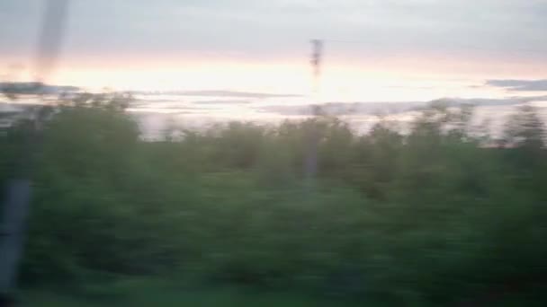 View from window of high-speed train on landscape of beautiful nature field and steel grain silos on evening dusk sky sunset in summer background. Transport, travel, railway, road, comnication concept — Stock Video