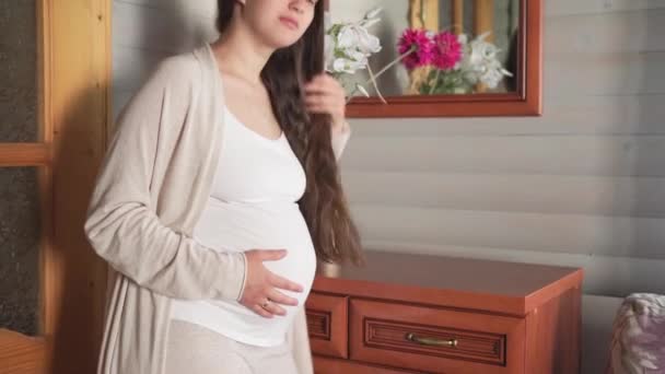 Beauté naturelle heureuse femme enceinte sans maquillage toucher le ventre à la maison près de la fenêtre. mère attentionnée caresse le gros ventre avec les mains sur la pièce lumineuse. grossesse, maternité, personnes, concept d'attente — Video