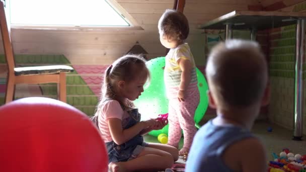 Petits enfants d'âge préscolaire frères et sœurs assis sur le sol avec des jouets dans la chambre des enfants. les gars jouent avec le constructeur dans la salle de jeux. Les enfants ont passé du bon temps à la maison. Enfance, amitié, concept de développement — Video