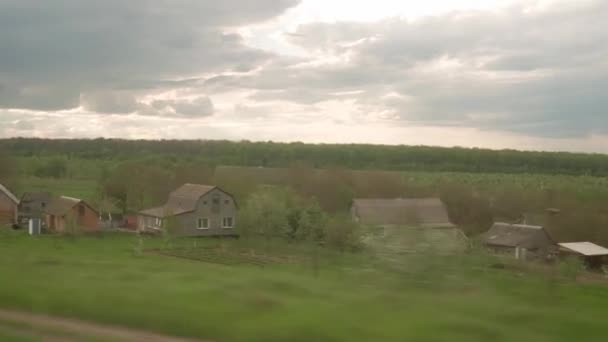 Vista da janela do trem de alta velocidade na paisagem da bela estrada de campo de natureza com carro e floresta no pôr do sol de céu crepúsculo da tarde em fundo de verão. Transporte, viagens, ferrovia, conceito de comunicação — Vídeo de Stock