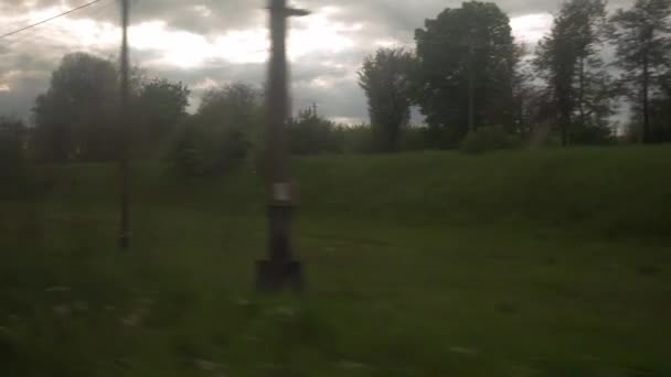 Vista dal finestrino del treno di velocità con abbagliamento su vetro sul bellissimo paesaggio di prato e bosco fiorito cielo nuvoloso in estate sfondo natura. Trasporto, viaggio, strada, ferrovia, concetto di comnicazione — Video Stock