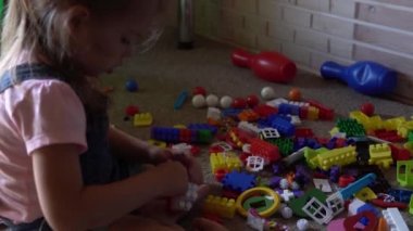Küçük anaokulu çocukları yerde ellerinde oyuncaklarla çocuk odasında oturuyorlar. Çocuklar oyun odasında inşaatçıyla oynuyorlar. Çocuklar evlerinde eğleniyorlar. Çocukluk, arkadaşlık, kalkınma kavramı
