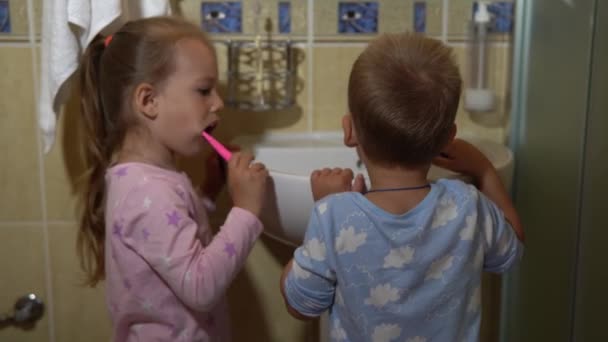 Porträt glücklich süße junge Vorschulkinder Simulationen Kinder Jungen und Mädchen Zähne putzen im Badezimmer und lächeln. Gesundheitsalltag für Kinder. Kaukasische Kinder waschen sich zu Hause vor dem Spiegel. Lebensstil — Stockvideo