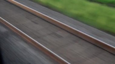 Hızlı trenin camında parlayan ışık ve yaz arkaplanındaki günbatımından önce çayırların ve ormanın manzarasında paralel raylar. Ulaşım, seyahat, yol, demiryolu, zina kavramı