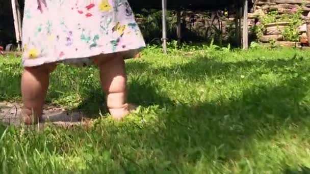 Close-up de pés de bebê andar descalço no gramado de grama verde de quintal ou jardim. A criança de câmera lenta caminha no prado sem sapatos. O bebê da criança dá os primeiros passos. Infância, família, vocação, conceito de esporte — Vídeo de Stock