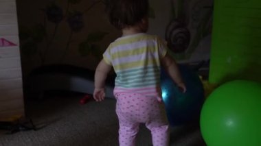 Küçük tatlı beyaz bebek kız ya da erkek çocuk odasında oyuncaklarla ödeme yapıyor. Oyun odasında büyük Fitnes topu olan çıplak ayaklı bir çocuk. Çocuk evde çok eğlenmiş. Çocukluk, arkadaşlık, kalkınma kavramı