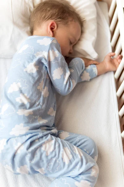 Vue du dessus Mignon petit garçon d'âge préscolaire de 2-3 ans dormant doucement dans un berceau blanc pendant la pause déjeuner en pyjama bleu avec oreiller à la maison. Enfance, loisirs, confort, médecine, concept de santé — Photo