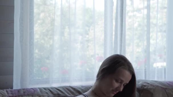 Cute happy tired pregnant woman touching her tummy resting sitting in bed at home. caring mother take rest stroke belly on light provence style room. pregnancy, motherhood, people, expectation concept — Stock Video