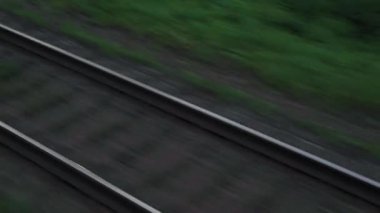 Pencereden yüksek hızlı tren manzarası güzel doğa manzarası vahşi arazi ve orman rayları yaz arkaplanında akşam günbatımında tren rayları. Ulaşım, seyahat, demiryolu, iletişim konsepti