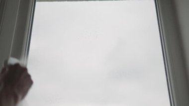 Evde cam silecekmiş. Uzun saçlı, sakallı genç bir adam daireyi temizliyor. Temizlik işçisi boş bir odadaki panoramik pencereleri dezenfekte ediyor. saflık, temizlik, konsepti değiştirme.