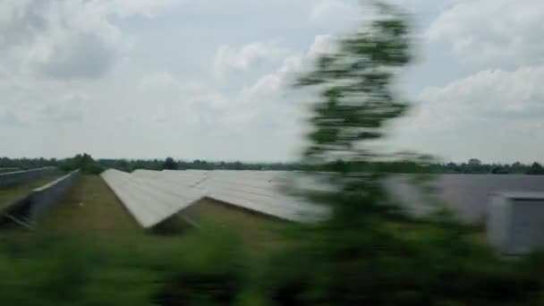 Vista da janela do trem de alta velocidade na paisagem de campo selvagem de natureza bonita e estação de fazenda de painel solar no pôr do sol em fundo de verão. Transporte, viagens, ferrovia, conceito de comunicação — Vídeo de Stock