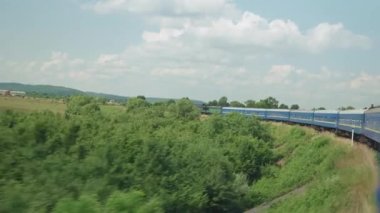 Yüksek hızlı trenin yan görüntüsü güzel doğa manzarası vahşi tarlalar ve dağların ormanı yaz arka planında güneşli bir günde. Ulaşım, seyahat, demiryolu, iletişim konsepti