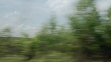 Yüksek hızlı trenin penceresinden manzarası güzel doğa manzarası vahşi tarlalar ve akşamları bulutlu, yaz arkaplanında güneşli bir gün. Ulaşım, seyahat, demiryolu, iletişim konsepti
