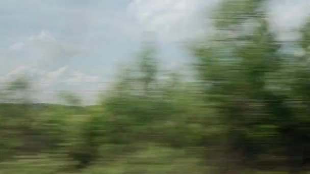 Vista da janela do trem de alta velocidade na paisagem da bela natureza campo selvagem e montanhas à noite nublado dia ensolarado limpo em fundo de verão. Transporte, viagens, ferrovia, conceito de comunicação — Vídeo de Stock