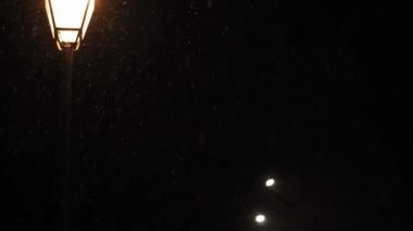 Hava tahmini, anomali, acil durum, element, kış konsepti - dengesiz bir kar fırtınası. Gece yolundaki sokak lambasının ışığında kar taneleri düşüyor. Kiev 'deki ilk kar
