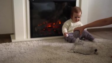 Bebek kediyle oynuyor. Erkek kedi halının üstünde, şöminenin yanında, konforunda. Çizgili kedi yavrusu iplik yumağıyla oynuyor. Kitty kameraya bakarak koş. Mutlu sevimli hayvan, çocukluk, vahşi doğa konsepti