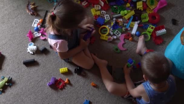 Małe przedszkolne rodzeństwo dzieci siedzące na podłodze z zabawkami w pokoju dziecięcym. Chłopaki bawią się z konstruktorem w pokoju zabaw. Dzieciaki spędzały miło czas w domu. Dzieciństwo, przyjaźń, koncepcja rozwoju — Wideo stockowe