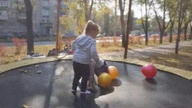 Sonbahar, spor, bayram, aile, çocukluk - iki mutlu küçük kardeş kardeş ikiz çocuklar trambolinde eğlenceli zıplama topları oynuyorlar güneşli bir akşam günbatımında parkta..