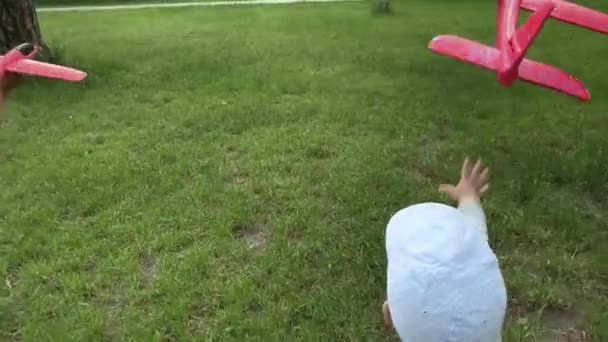 Üç mutlu anaokulu çocuğu kardeş çocuklar yaz parkında koşuşturan çocuklar çayırda oynuyorlar oyuncak uçaklarla gökyüzüne uçuyorlar. Çocukluk, arkadaşlık, dinlenme, doğa. — Stok video