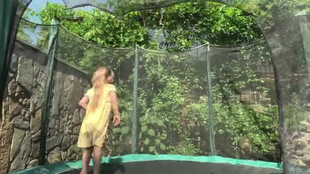 Cute Happy Kid Little Preschool Baby Girl in Yellow Dress Child Jogar Divirta-se pulando no trampolim fora da tarde ensolarada no parque. Crianças jogos de quintal. Verão, Esportes, Feriado, Família, Infância. — Vídeo de Stock