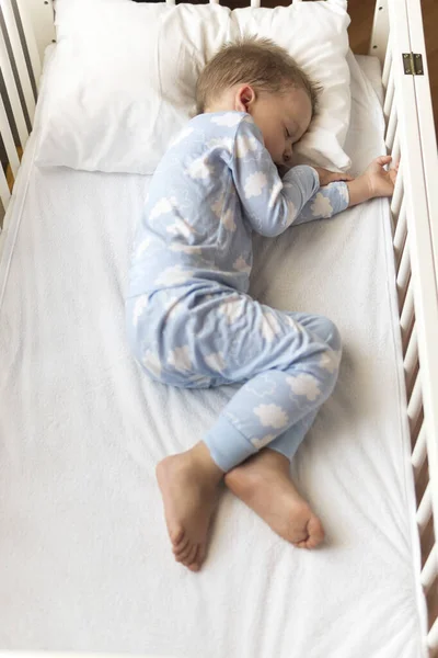 Top view Aranyos kis 2-3 éves óvodás fiú gyerek alszik édesen fehér bölcsőben ebédidő alatt pihenő kék pizsamában párnával otthon. Gyermekkor, szabadidő, kényelem, orvostudomány, egészség fogalma — Stock Fotó
