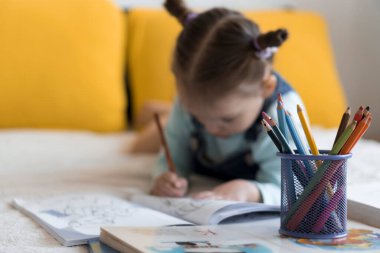 Zeki, gülümseyen, küçük bir çocuk çocuk ve kız sarı yatakta göbeklerinde kalemlerle resim yapıyorlar. Küçük sevimli okuyucu evde karantinada eğleniyor, mutlu çocuk. Arkadaşlık, aile, eğitim.