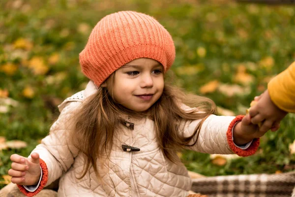 Retrato de pequena menina pré-escolar bonito em laranja boina em folhas caídas amarelas leva a maçã de alguém olha para longe em tempo frio em Fall Park. Infância, Família, Maternidade, Conceito de outono — Fotografia de Stock